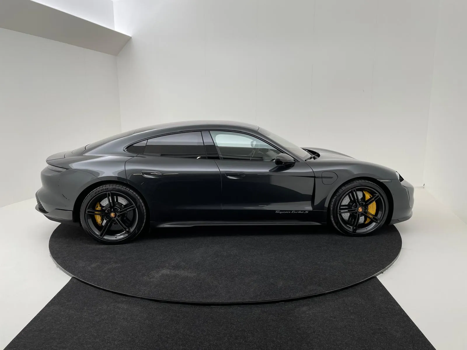 Grijze Porsche Taycan op de draaischijf in de fotostudio